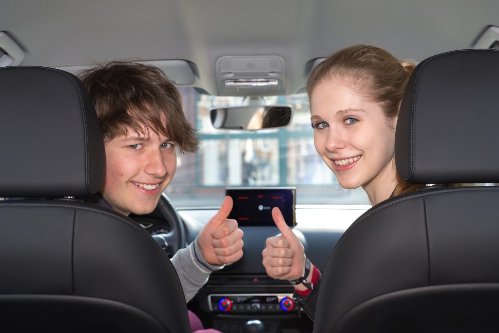 Fahrschüler im Auto zeigen den Daumen nach oben